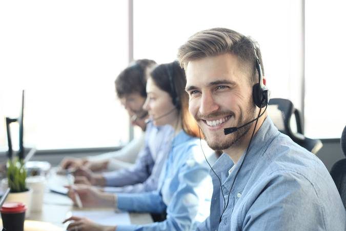 Portrait of call center worker accompanied by his team. Smiling customer support operator at work